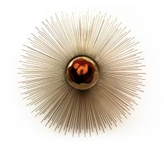 Brilliance Sconce with gold spines that fan out around the light source from Koket