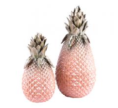 Two metallic pineapple accessories, one large and one small, with green tops and pink bases from Zuo Modern