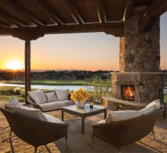Patio with furniture and fireplace overlooking golf course at sunset