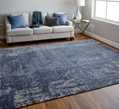 Blue and off-white rug on a hardwood floor. There is an off-white couch with blue and gray pillows.