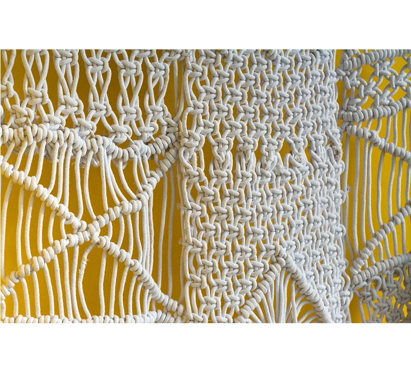 Macrame wall hanging in white on a yellow background from Gold Leaf Design Group 