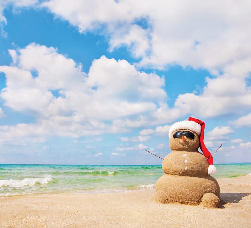 Sandman wearing Santa hat and sunglasses on beach
